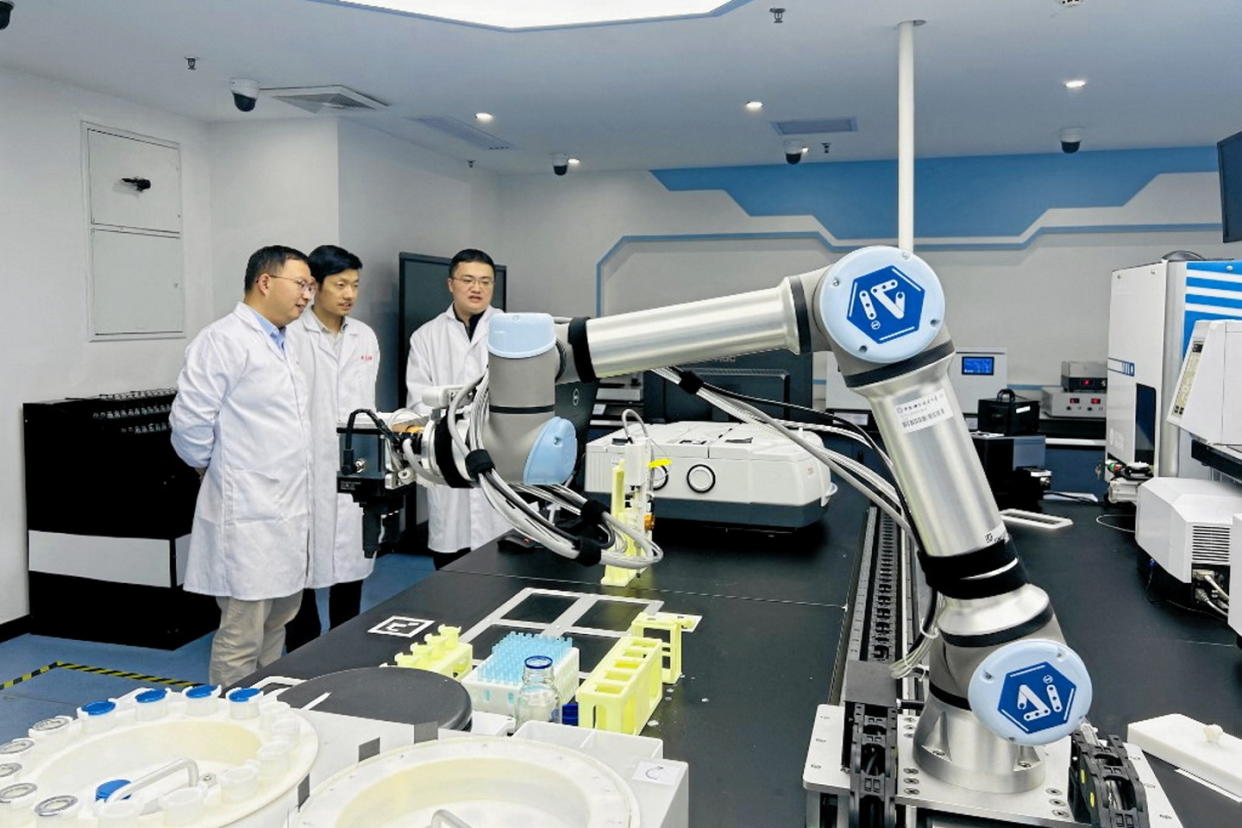 Des chercheurs chinois travaillent au côté de leur robot chimiste piloté par l'IA à l'université des sciences et technologies de Chine à Hefei, dans la province de l'Anhui (est de la Chine), le 10 novembre 2023.  - Credit:ZHOU CHANG / XINHUA / Xinhua via AFP