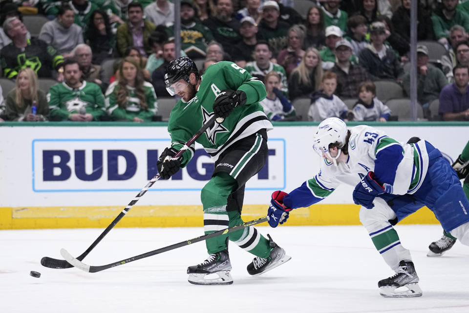 Dallas Stars center Tyler Seguin (91) shoots as Vancouver Canucks' Quinn Hughes (43) defends during the first period of an NHL hockey game, Monday, Feb. 27, 2023, in Dallas. (AP Photo/Tony Gutierrez)
