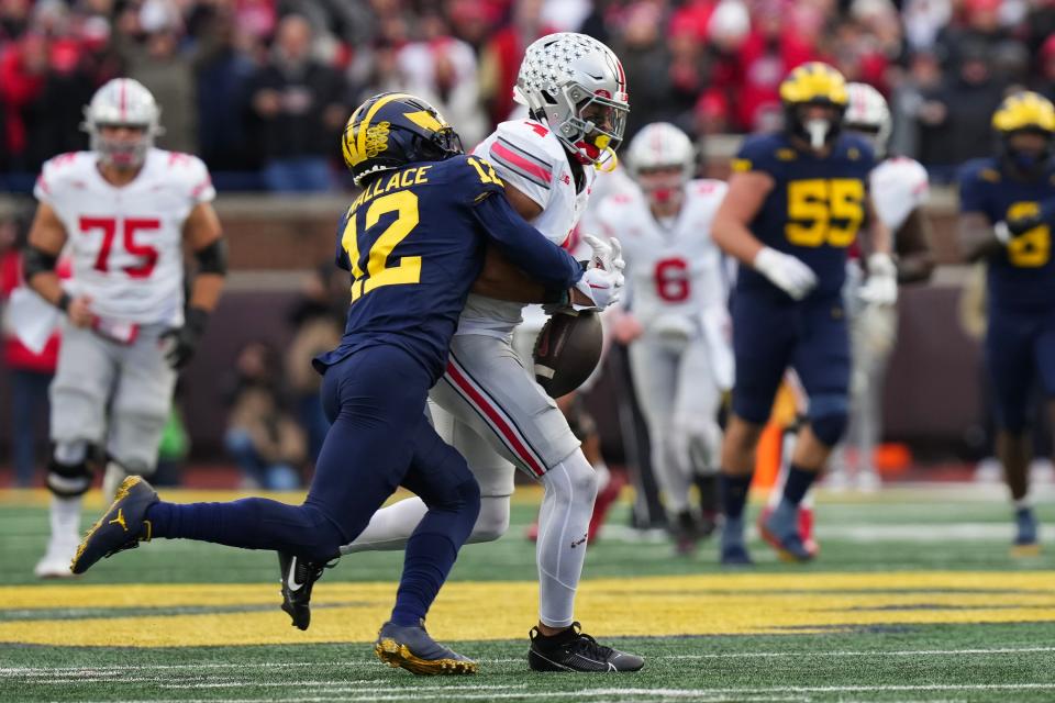 Nov 25, 2023; Ann Arbor, Michigan, USA; Michigan Wolverines defensive back Josh Wallace (12) forces a fumble by Ohio State Buckeyes wide receiver Julian Fleming (4) during the NCAA football game at Michigan Stadium. Ohio State lost 30-24.