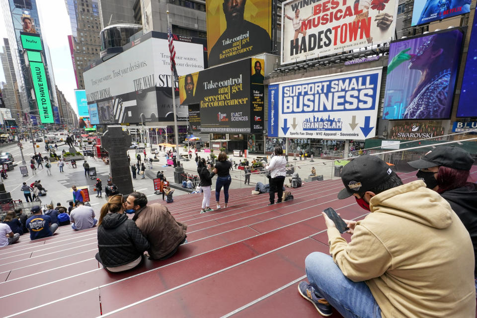 Visitors to New York's Time Square take in the view from the TKTS stairway, Tuesday, April 27, 2021, in New York. In recent weeks, tourism indicators for New York City like hotel occupancy and museum attendance that had fallen off a pandemic cliff have ticked up slightly. It's a welcome sight for a city where the industry has been decimated by the impact of the coronavirus. (AP Photo/Mary Altaffer)