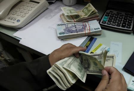 FILE PHOTO: A currency exchange trader counts money at his office in Islamabad November 26, 2012. REUTERS/Faisal Mahmood/File Photo