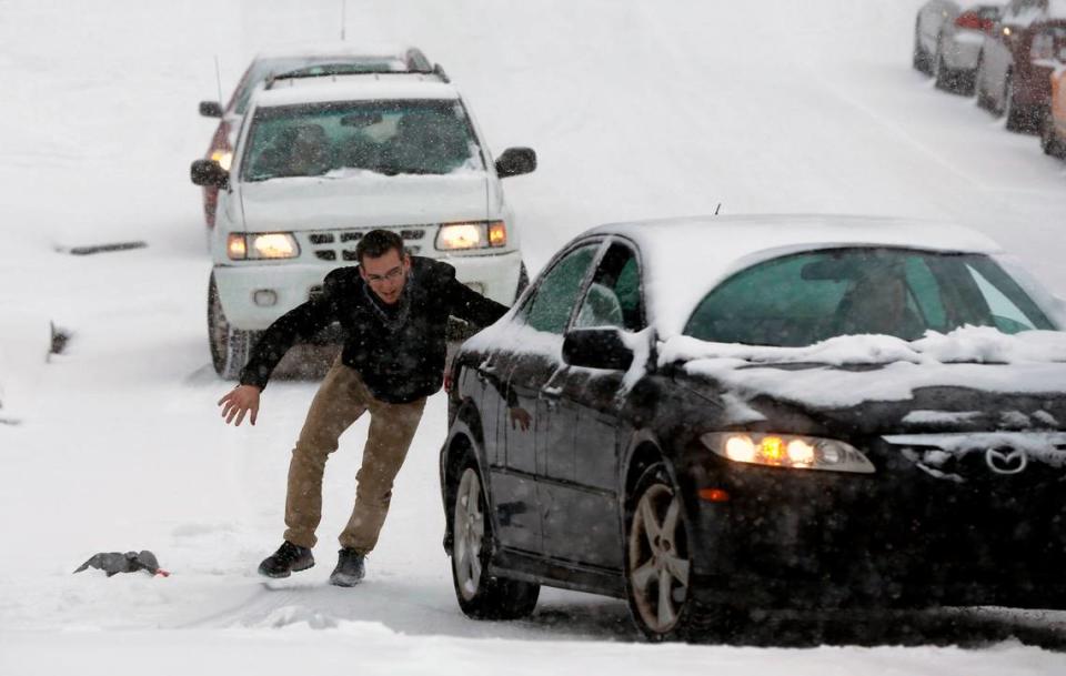 Robert Moss, left, and Isaac Granick (behind car) help Dan Schneider navigate his car up W. Hargett St. in the snow in Raleigh, Wednesday, February 12, 2014. Ethan Hyman/ehyman@newsobserver.com