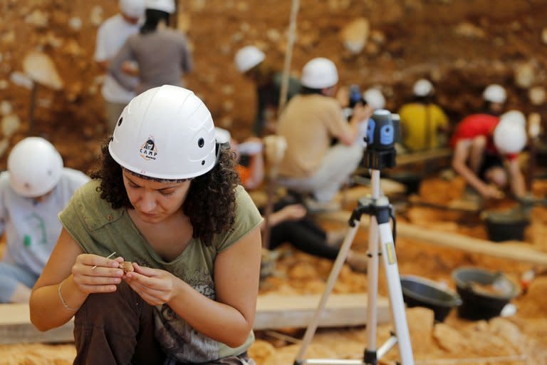 Workers carry out an excavation at the Gran Dolonia site in the caves of Atapuerca on July 11, 2013. With trowels and paintbrushes, dozens of archaeologists in white hard-hats patiently sift the reddish-brown earth, searching for remains a million years old