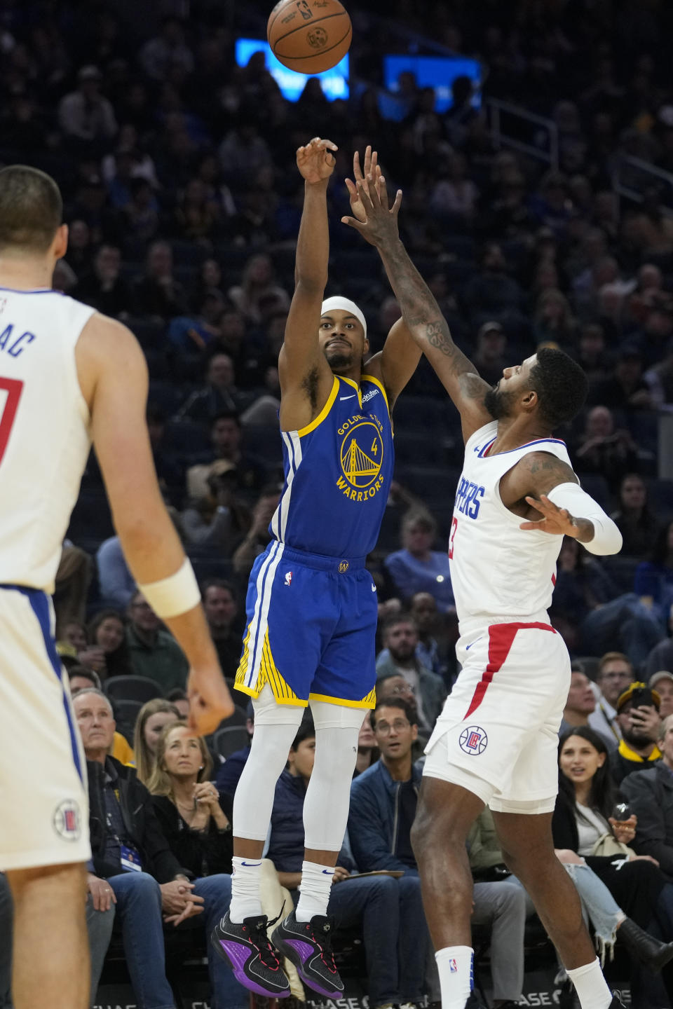 Golden State Warriors guard Moses Moody (4) shoots a 3-point basket over Los Angeles Clippers forward Paul George, right, during the first half of an NBA basketball game Thursday, Nov. 30, 2023, in San Francisco. (AP Photo/Godofredo A. Vásquez)