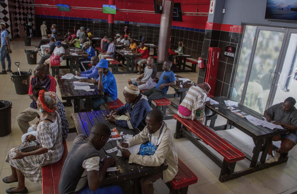 Customers place their bets and watch screens inside a sports betting shop in the Soweto township of Johannesburg, South Africa, Thursday, Dec. 8, 2022. Although sports betting is a global phenomenon and a legitimate business in many countries, the stakes are high on the continent of 1.3 billion people because of lax or non-existent regulation, poverty and widespread unemployment. (AP Photo/Denis Farrell)