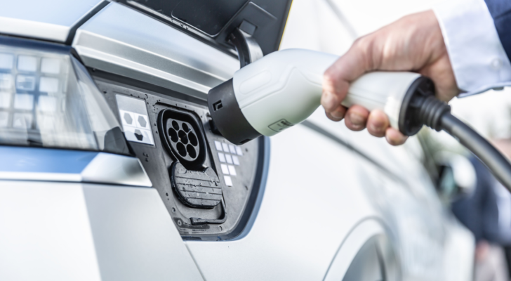 The driver of the electric car inserts the electrical connector to charge the batteries. Electric vehicle charger