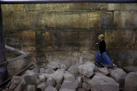 Israel Antiquities Authority archaeologist Tehillah Lieberman walks atop stones lying besides a part of the Western Wall, during a media tour revealing a theatre-like structure which was discovered during excavation works underneath Wilson's Arch in the Western Wall tunnels in Jerusalem's Old City October 16, 2017. REUTERS/Ronen Zvulun