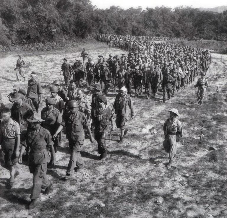 Captured French soldiers, escorted by Vietnamese soldiers, walk to a prisoner of war camp in Dien Bien Phu, May 1954