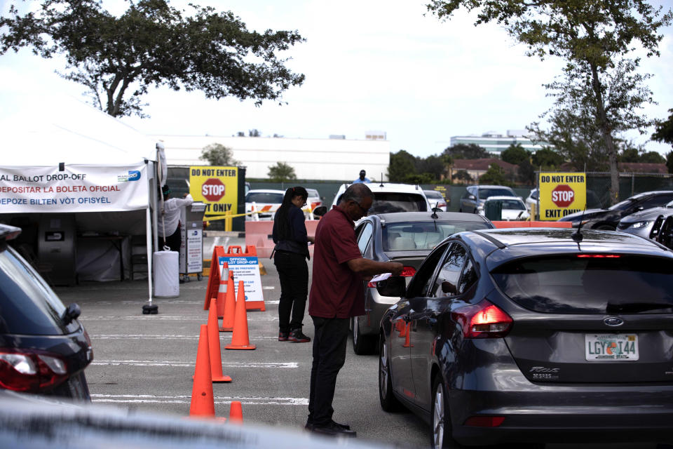 Drivers line up in their cars to drop off ballots.