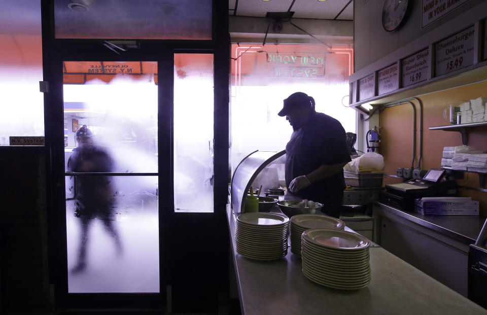 In this Monday, March 3, 2014 photo Nicholas Barros, a waiter and cook at Olneyville New York System of Providence works the grill as a customer walks up to the door in Providence, R.I. The James Beard Foundation named the Rhode Island restaurant one of five "American Classics" this year as best known for hot wieners. (AP Photo/Stephan Savoia)