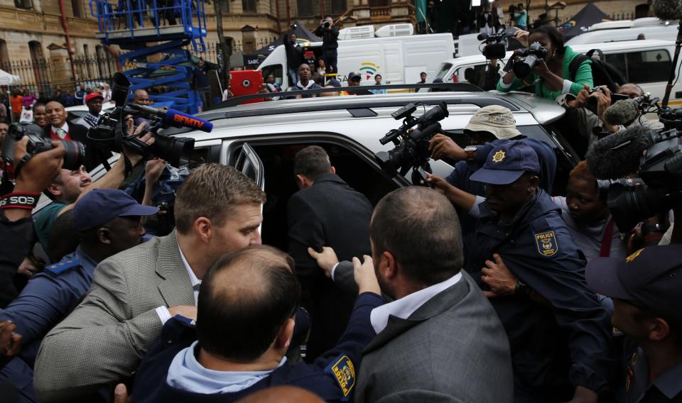 Members of the media photograph Olympic and Paralympic track star Oscar Pistorius (C) as he leaves after his trial at the North Gauteng High Court in Pretoria March 4, 2014. Pistorius is on trial for murdering his girlfriend Reeva Steenkamp at his suburban Pretoria home on Valentine's Day last year. He says he mistook her for an intruder. REUTERS/Siphiwe Sibeko (SOUTH AFRICA - Tags: CRIME LAW MEDIA SPORT ATHLETICS)