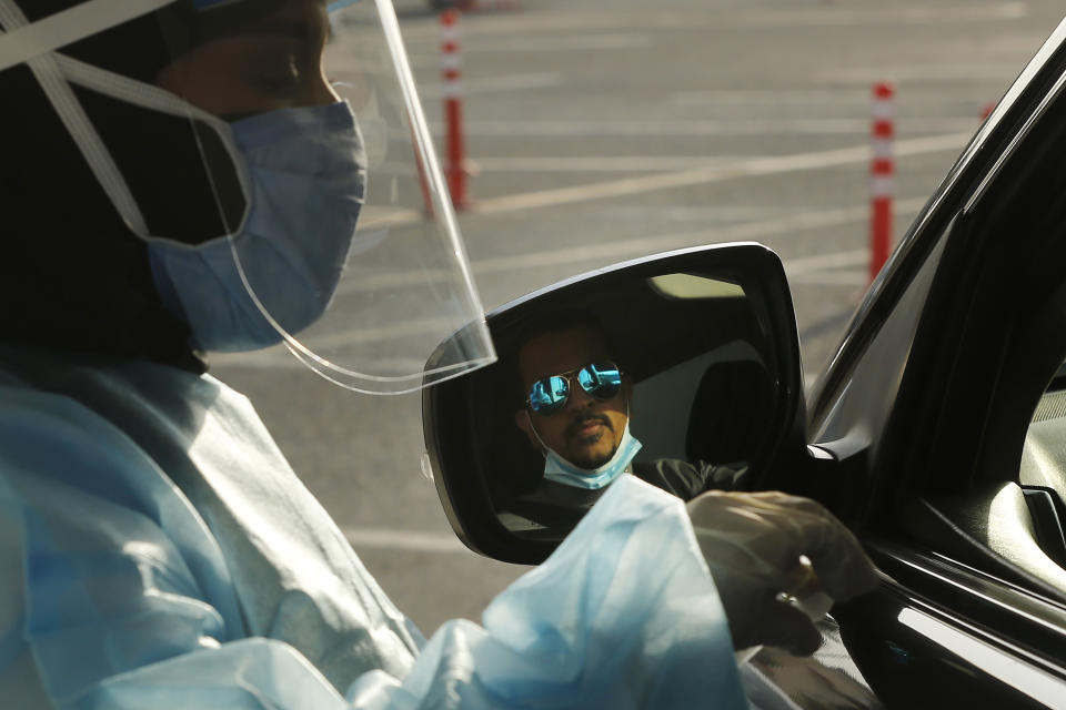 Saudi health worker, Wedad Modaifen prepares to collect a swab sample for a polymerase chain reaction (PCR) test at drive-through testing center at King Abdulaziz University in Jiddah, Saudi Arabia Wednesday, Feb. 3, 2021. In Saudi Arabia, where authorities already have banned travel to the kingdom from 20 countries including the U.S., officials ordered all weddings and parties suspended. It closed down all shopping malls, gyms and other locations for 10 days, as well as indoor dining. Authorities warned the new measures could be extended. (AP Photo/Amr Nabil)