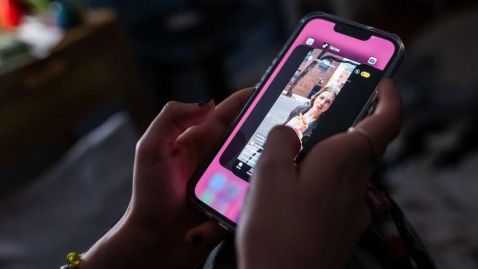 Photo illustration of a teenager using TikTok on her mobile phone