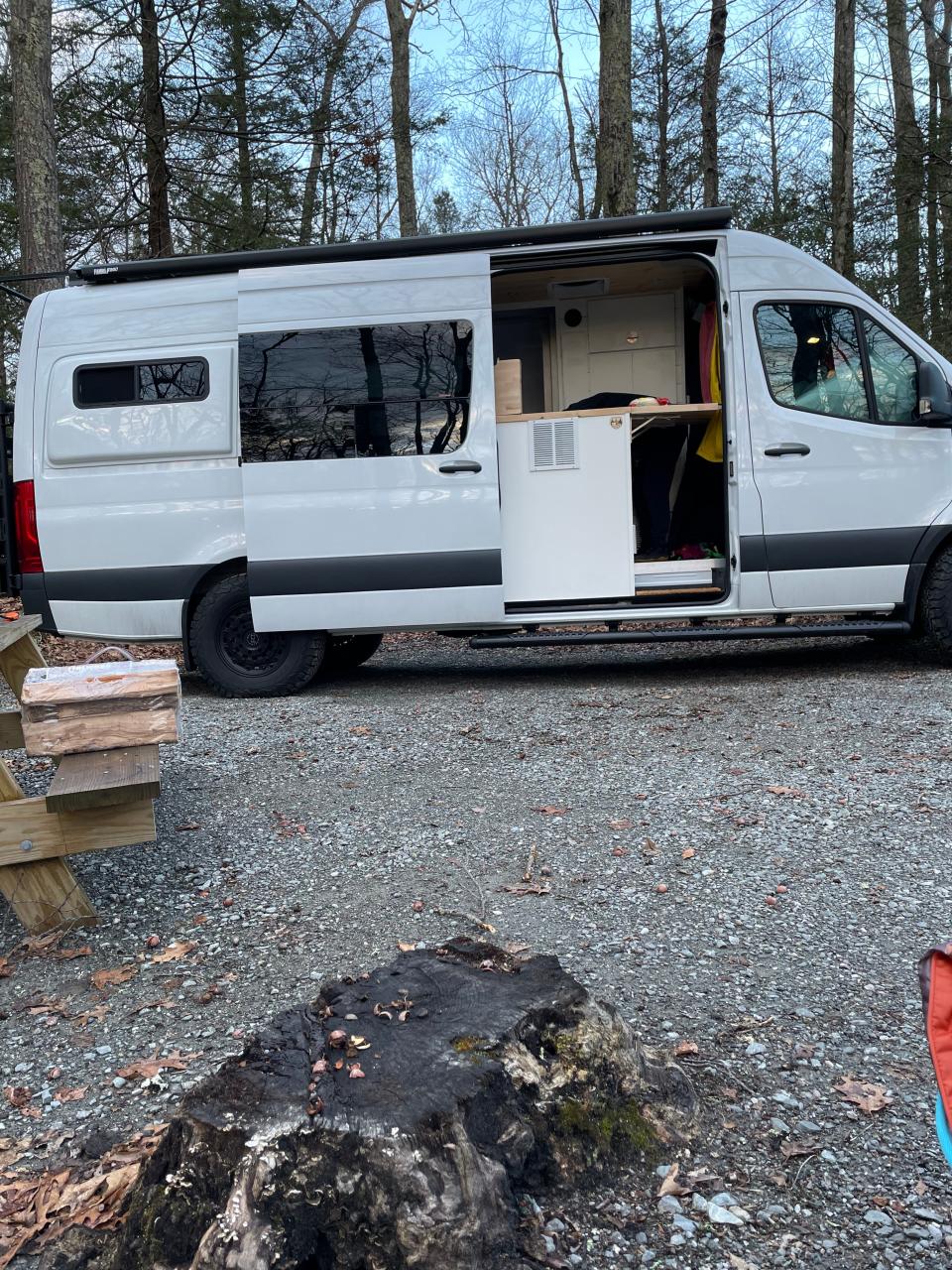 The sprinter van with its side door open in the woods