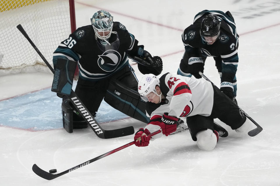 New Jersey Devils center Curtis Lazar (42) shoots the puck against San Jose Sharks goaltender Kaapo Kahkonen (36) and defenseman Henry Thrun (3) during the third period of an NHL hockey game in San Jose, Calif., Tuesday, Feb. 27, 2024. (AP Photo/Jeff Chiu)