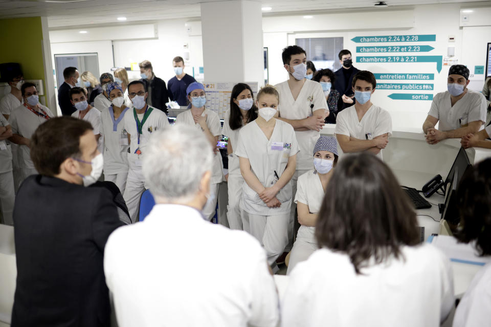 French President Emmanuel Macron, left, speaks with staff working in the intensive care ward of the Poissy/Saint-Germain-en-Laye hospital, near Paris, Wednesday, March 17, 2021. With the virus rebounding from Paris to Budapest and beyond, European governments that rushed to suspend use of AstraZeneca vaccines after reports of blood clots are realizing the far-reaching impact of the move. (Yoan Valat, Pool via AP)