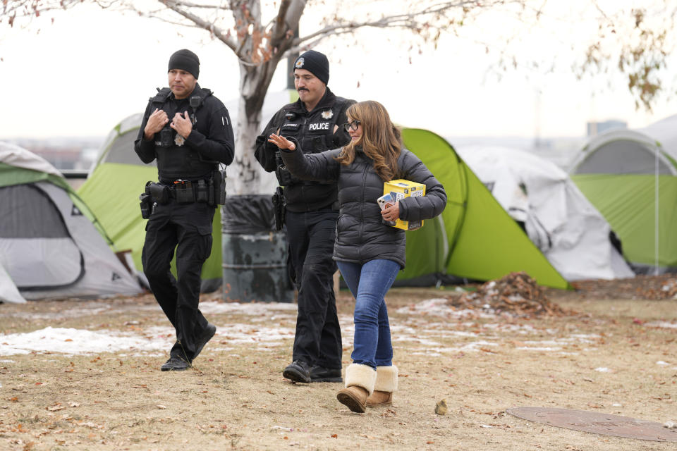 Denver City Councilperson Amanda Sandoval, right, joins a pair of Denver Poice Department officers during a city-sponsored sweep of an encampment overlooking the city skyline on Diamond Hill Wednesday, Nov. 1, 2023, in Denver. The sweep was just one of several staged in various locations across the Mile High City. (AP Photo/David Zalubowski)
