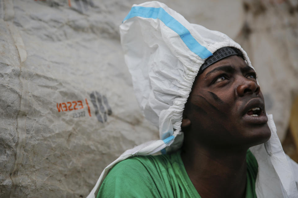 Isaac Kivai, who scavenges recyclables for a living, wears a protective suit found in the trash at Dandora, the largest garbage dump in the Kenyan capital of Nairobi, Sunday, March 28, 2021. Trash pickers, who are not eligible for the COVID-19 vaccine, say the gear protects them from the weather during the rainy season. (AP Photo/Brian Inganga)