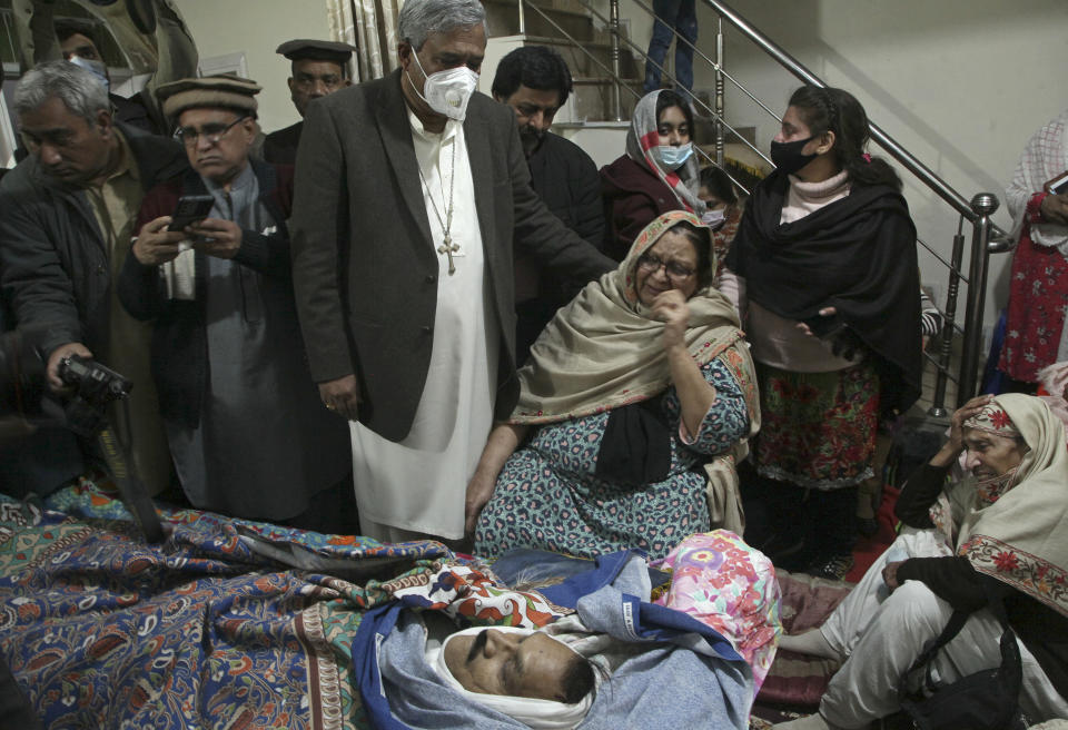 Relatives of Christian priest Father William Siraj, 75, who was killed by unknown gunmen, mourn next to his body at his home in Peshawar, Pakistan, Sunday, Jan. 30, 2022. Police said gunmen killed Siraj and wounded another priest as they were driving home from Sunday Mass in Pakistan’s northwestern city of Peshawar. (AP Photo/Muhammad Sajjad)