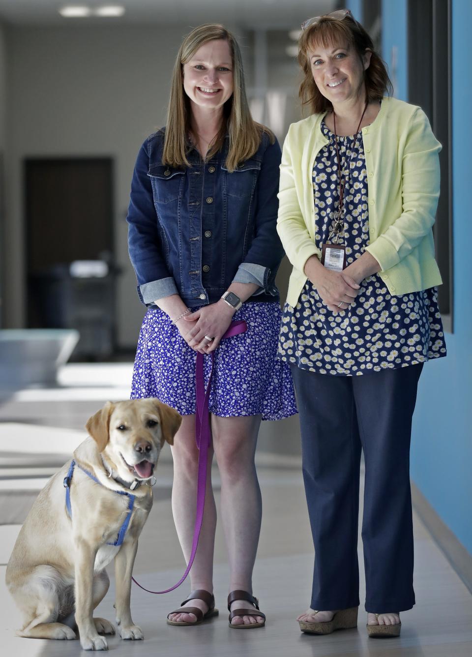 Menasha High School's new therapy dog, Prada, hangs out with counselor Lauren Schultz, left, and teacher Erin Culligan.