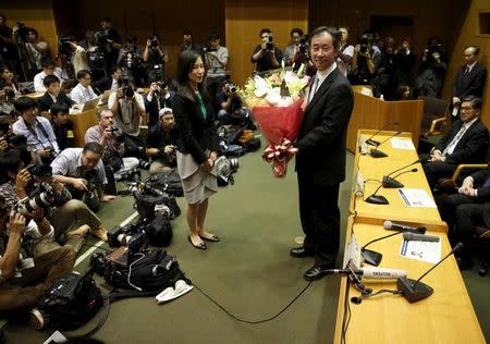 Takaaki Kajita (R), director of the University of Tokyo's Institute for Cosmic Ray Research, receives flowers from his university during a news conference in Tokyo October 6, 2015. REUTERS/Issei Kato