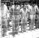 FILE - In this B/W file photo dated Aug. 15, 1945, Japanese prisoners of war at Guam, Mariana Islands, bow their heads as they hear Japanese Emperor Hirohito making the announcement of Japan's unconditional surrender. Saturday Aug. 15, 2020, British Prime Minister Boris Johnson has paid tribute to surviving veterans of the multinational Allied campaign against Japan in World War II, which ended 75 years ago. Following the defeat of the Nazis on May 8, 1945, Allied troops carried on fighting until Japan’s surrender, but many of them felt their efforts had not been fully recognized and dubbed themselves the “forgotten army.” (AP Photo/FILE)