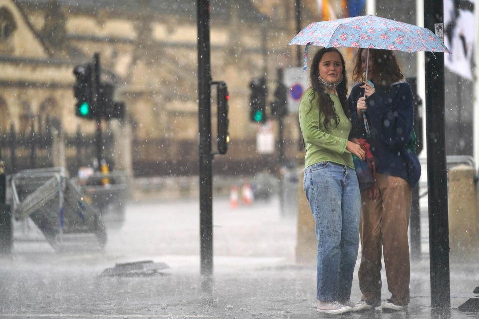 <p>Two young women shelter under an umbrella in Parliament Square as heavy rain sweeps through central London. Thunderstorms bringing lightning and torrential rain to the south are set to continue until Monday, forecasters have said. Picture date: Sunday July 25, 2021. (Photo by Victoria Jones/PA Images via Getty Images)</p>
