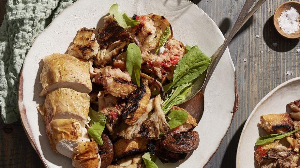 grilled mushroom panzanella with tomato vinaigrette on a white plate with silverware