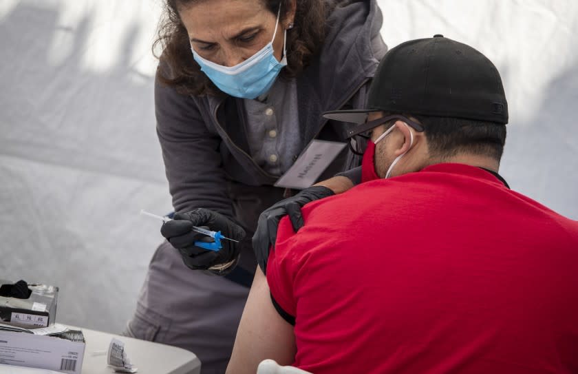 LOS ANGELES, CA - MARCH 18: Pharmacist Nasrin Assil, left, administers a Johnson & Johnson COVID-19 vaccine at Karsh Family Social Service Center's pop-up clinic for older adults in the neighborhood on Thursday, March 18, 2021 in Los Angeles, CA., left. (Brian van der Brug / Los Angeles Times)