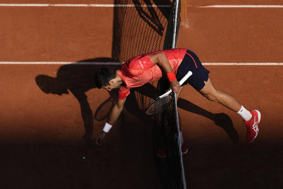 Serbia's Novak Djokovic picks up an object from the clay court during his third round match of the French Open tennis tournament against Spain's Alejandro Davidovich Fokina at the Roland Garros stadium in Paris, Friday, June 2, 2023. (AP Photo/Christophe Ena)