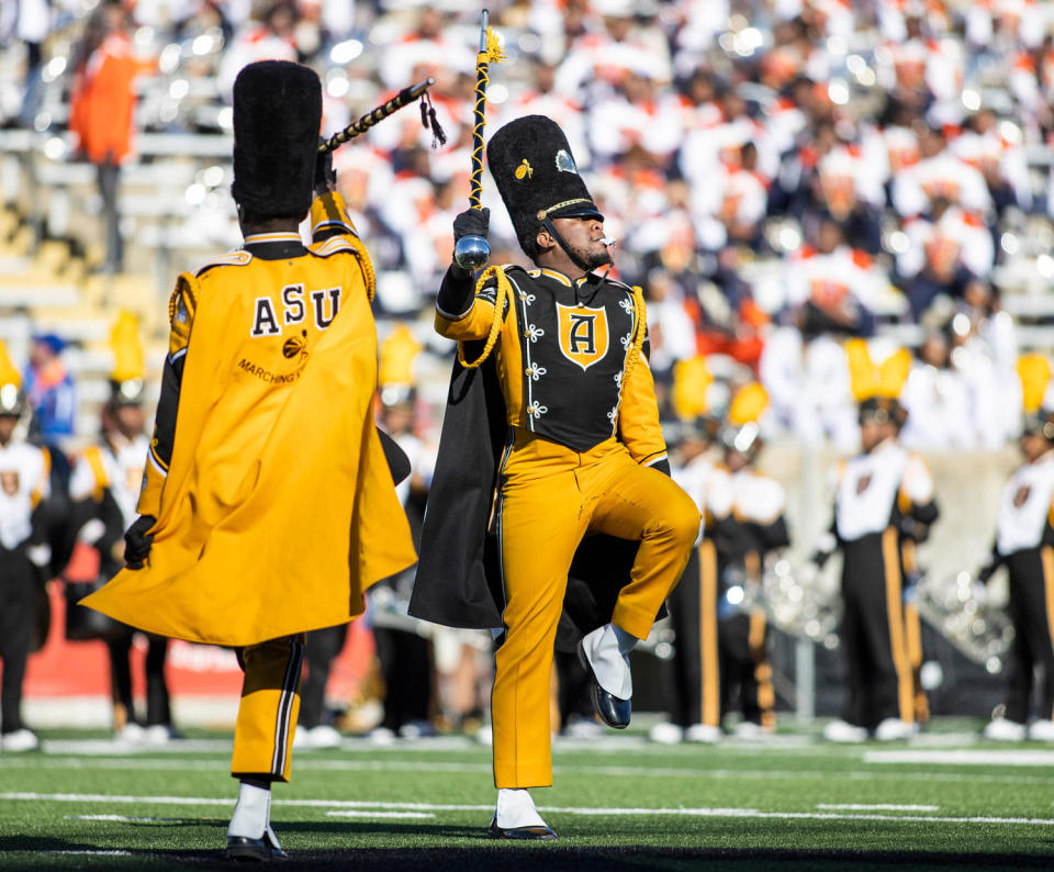 The Arizona State University marching band marches on a football field in yellow and black costumes (American Honda)