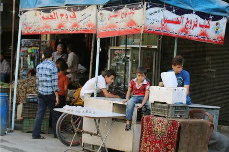 A boy looks on, inside a market in the rebel-held al-Shaar neighbourhood of Aleppo, Syria, September 17, 2016. Picture taken September 17, 2016. The sign reads in Arabic:" Hussein's Kebab and chicken". REUTERS/Abdalrhman Ismail