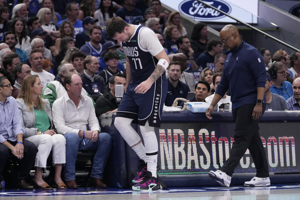 Dallas Mavericks' Luka Doncic slowly walks off the court with a staff member during the first half of Game 2 of the team's NBA basketball first-round playoff series against the Los Angeles Clippers in Dallas, Friday, April 26, 2024. Doncic continued playing in the half. (AP Photo/Tony Gutierrez)