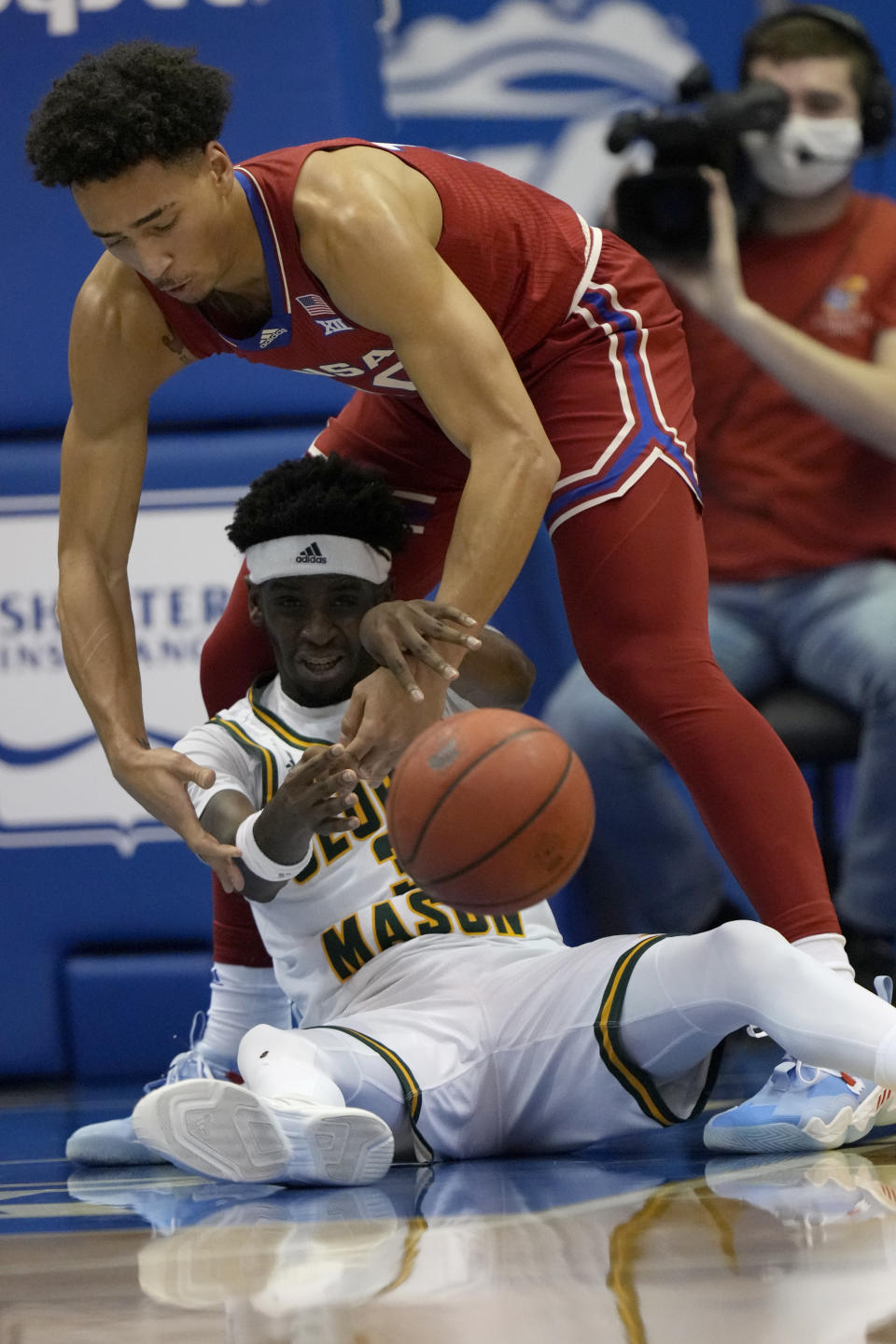George Mason guard Davonte Gaines (3) passes to a teammate while covered by Kansas forward Jalen Wilson (10) during the first half of an NCAA college basketball game in Lawrence, Kan., Saturday, Jan. 1, 2022. (AP Photo/Orlin Wagner)