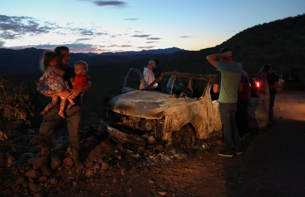 Members of the LeBaron family look at the burned car where part of the nine murdered members of the family were killed and burned during an ambush in Bavispe, Sonora mountains, Mexico, on November 5, 2019. - US President Donald Trump offered on November 5 to help Mexico "wage war" on its cartels after three women and six children from an American Mormon community were murdered in an area notorious for drug traffickers. (Photo by Herika MARTINEZ / AFP) / The erroneous mention appearing in the metadata of this photo has been modified in AFP systems in the following manner: byline should read [Herika MARTINEZ] instead of [STRINGER]. Please immediately remove the erroneous mention from all your online services and delete it from your servers. If you have been authorized by AFP to distribute it to third parties, please ensure that the same actions are carried out by them. Failure to promptly comply with these instructions will entail liability on your part for any continued or post notification usage. Therefore we thank you very much for all your attention and prompt action. We are sorry for the inconvenience this notification may cause and remain at your disposal for any further information you may require. (Photo by HERIKA MARTINEZ/AFP via Getty Images)