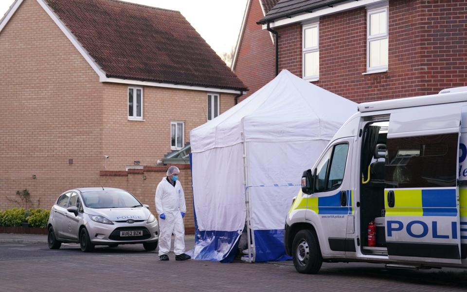 A forensic investigator outside a house in Costessey near Norwich after four people were found dead inside the property