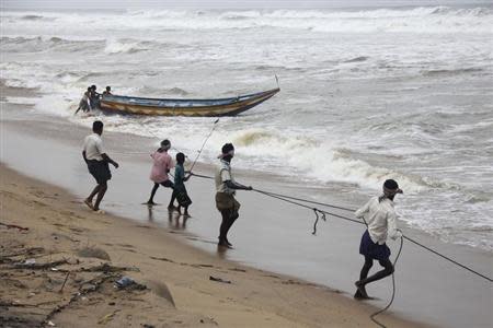 Fishermen pull a boat from the waters of the Bay of Bengal to safer ground at Podampata village in Ganjam district in the eastern Indian state of Odisha October 11, 2013. REUTERS/Stringer