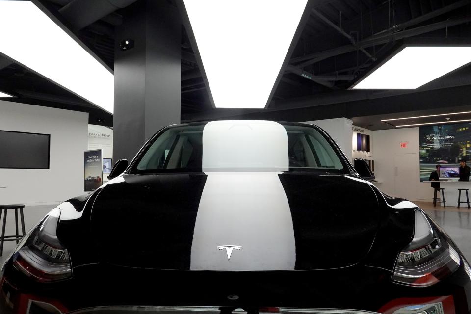 A black Tesla Model Y electric vehicle under a bright light in a showroom