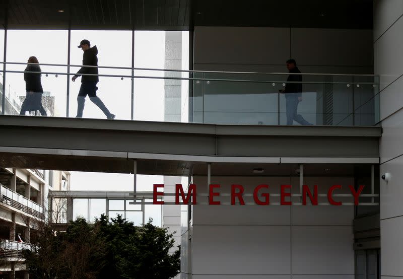 People walk on a skybridge from the emergency room building at Providence Regional Medical Center after coronavirus victim treated in Everett