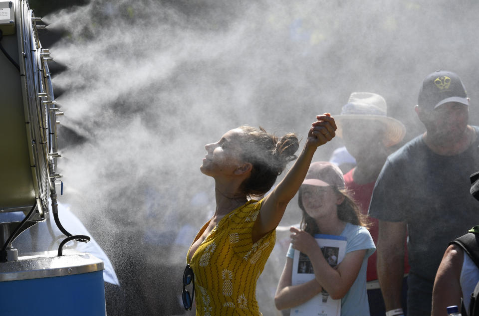 In this Jan. 14, 2019, file photo, spectators cool themselves down with a water mist fan during play on day one at the Australian Open tennis championships in Melbourne, Australia. Australia has sweltered through its hottest month on record in January and the summer of extremes continues with wildfires razing the drought-parched south while expanses of the tropical north are flooded. Australia’s Bureau of Meteorology confirmed the record heat during January as parts of the northern hemisphere have had record cold. (AP Photo/Andy Brownbill, File)