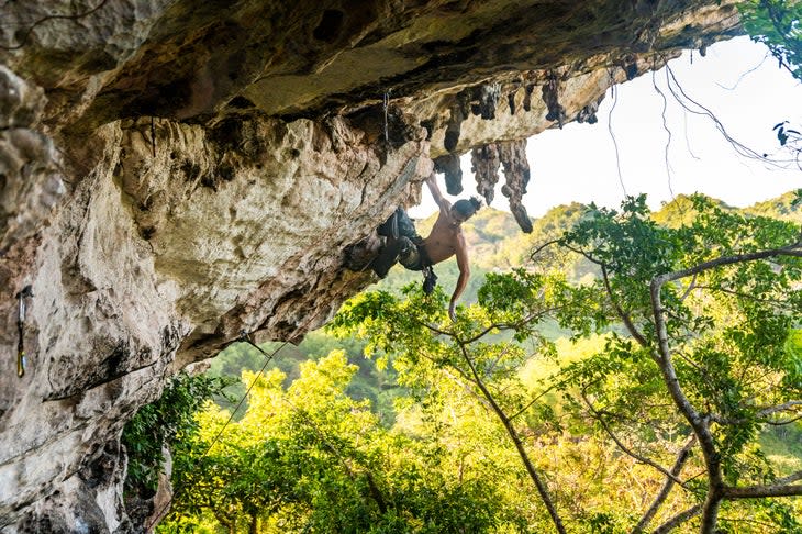 Man climbs limestone cave in Jamaica.