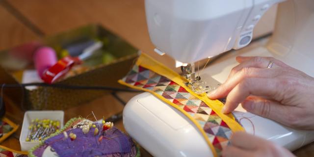 Premium Photo  Hands of a dressmaker sewing clothes from white fabric on a sewing  machine closeup