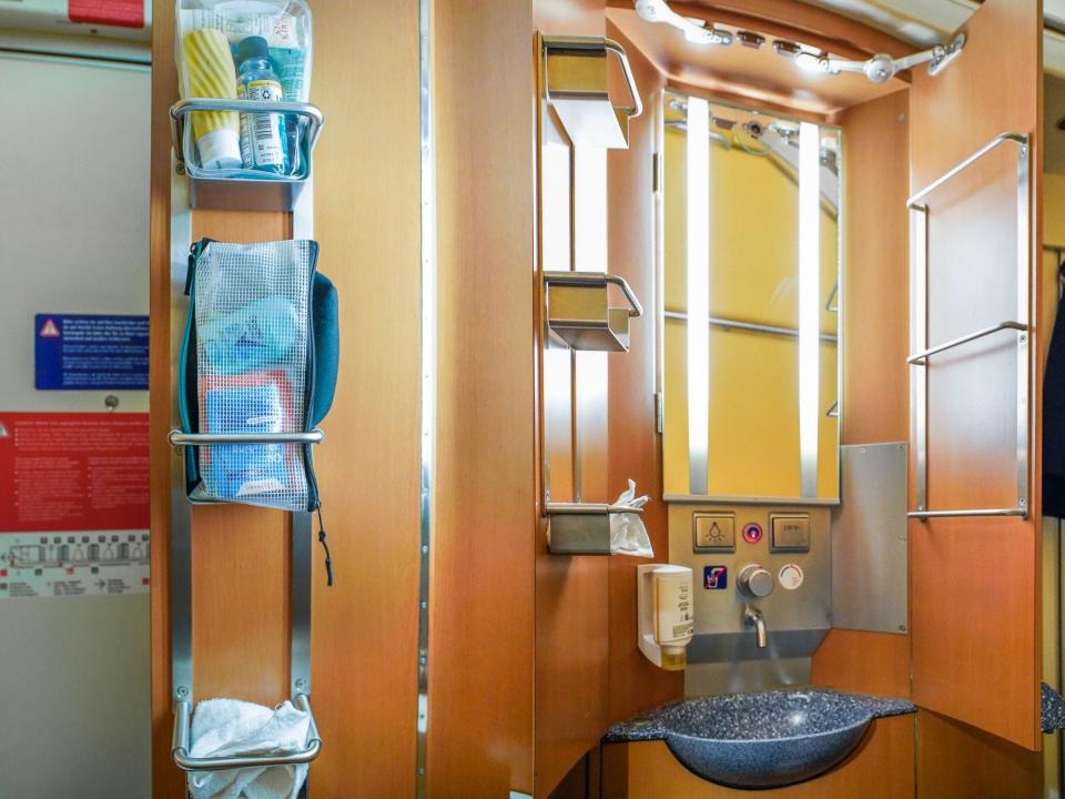 Toiletries are stored in a wooden vanity with a mirror and a wash basin