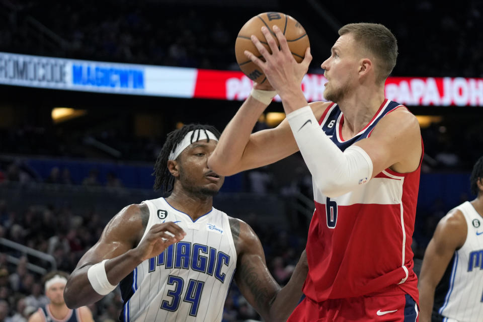 Washington Wizards' Kristaps Porzingis, right, takes a shot over Orlando Magic's Wendell Carter Jr. (34) during the second half of an NBA basketball game, Tuesday, March 21, 2023, in Orlando, Fla. (AP Photo/John Raoux)