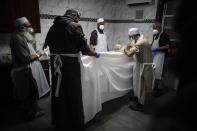 The body of Mohammad Altaf, who died at 48 of COVID-19, is ritually washed and wrapped before being given funeral prayers at Al-Rayaan Muslim Funeral Services, Sunday, May 17, 2020, in the Brooklyn borough of New York. (AP Photo/John Minchillo)