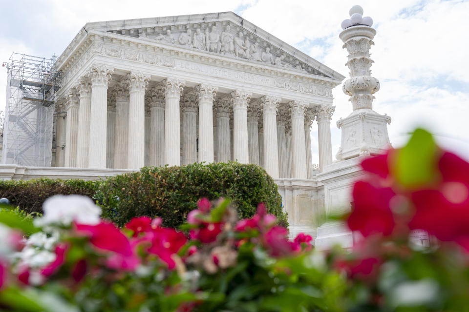 The Supreme Court is seen behind flowers, Tuesday, June 27, 2023, in Washington, as decisions are expected. (AP Photo/Jacquelyn Martin)