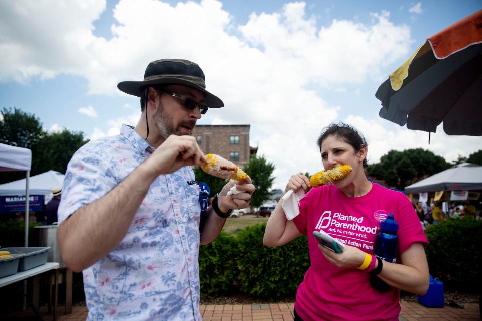 Dave and Erin Owen, of Cedar Rapids, eat sweet corn before listening to presidential candidates during at the annual Progress Iowa Corn Feed on Sunday, July 14, 2019, outside New Bo City Market in Cedar Rapids. 