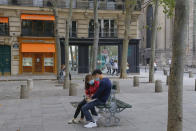 A couple sit on a bench while wearing a protective face masks as a precaution against the coronavirus in Paris, Wednesday, Aug. 19, 2020. The French government is trying to contain growing virus infections but avoid shutting down the economy. (AP Photo/Michel Euler)