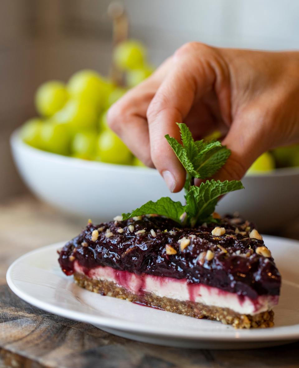 Chef Lisa Brown, owner of Cape Coral-based Free Flowing Health, garnishes a slice of cheesecake with cardamom, cashew cream, hazelnut crust, topped with cherry compote.