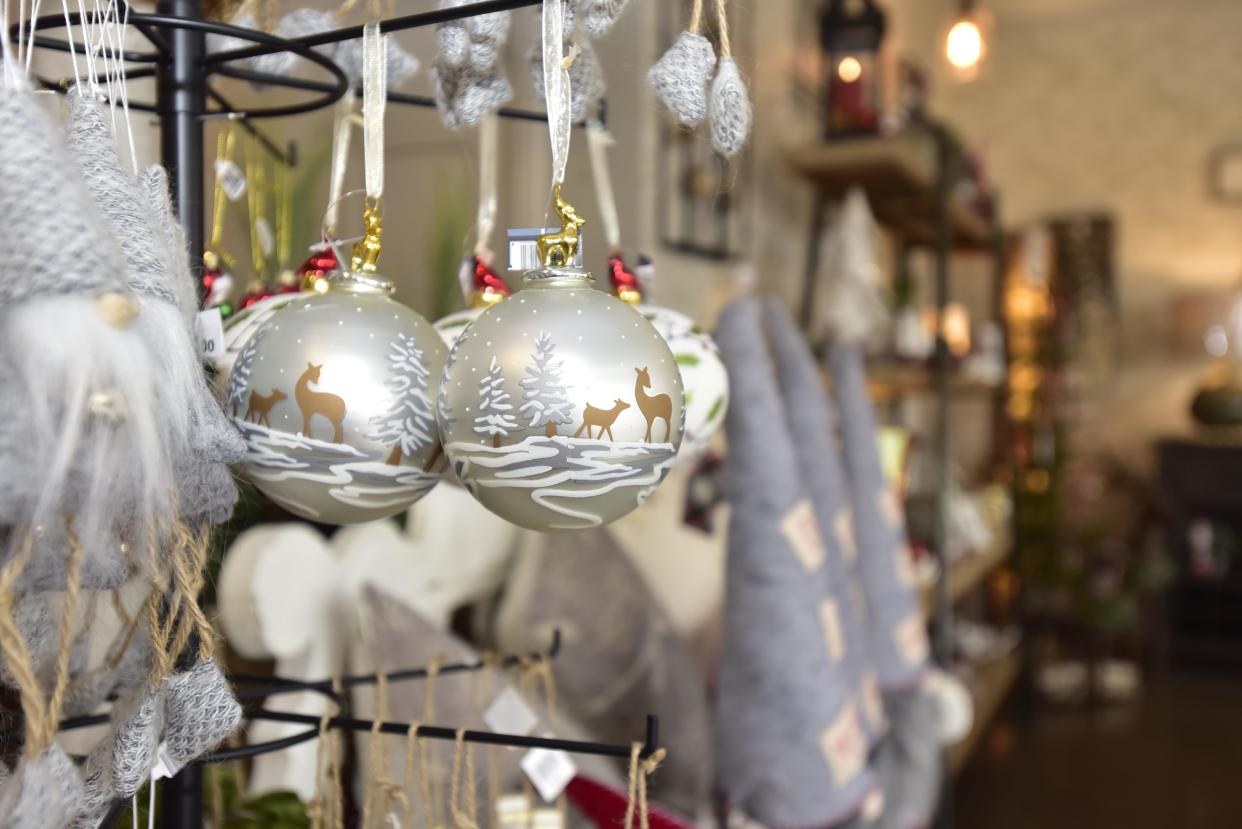 Christmas tree ornaments hang off a stand at the home décor boutique the Lazy Llama located at 214 Broadway St. in Marine City on Monday, Dec. 5, 2022. The year has been dominated by headlines about rising costs of inflation and concerns about a future economic recession.